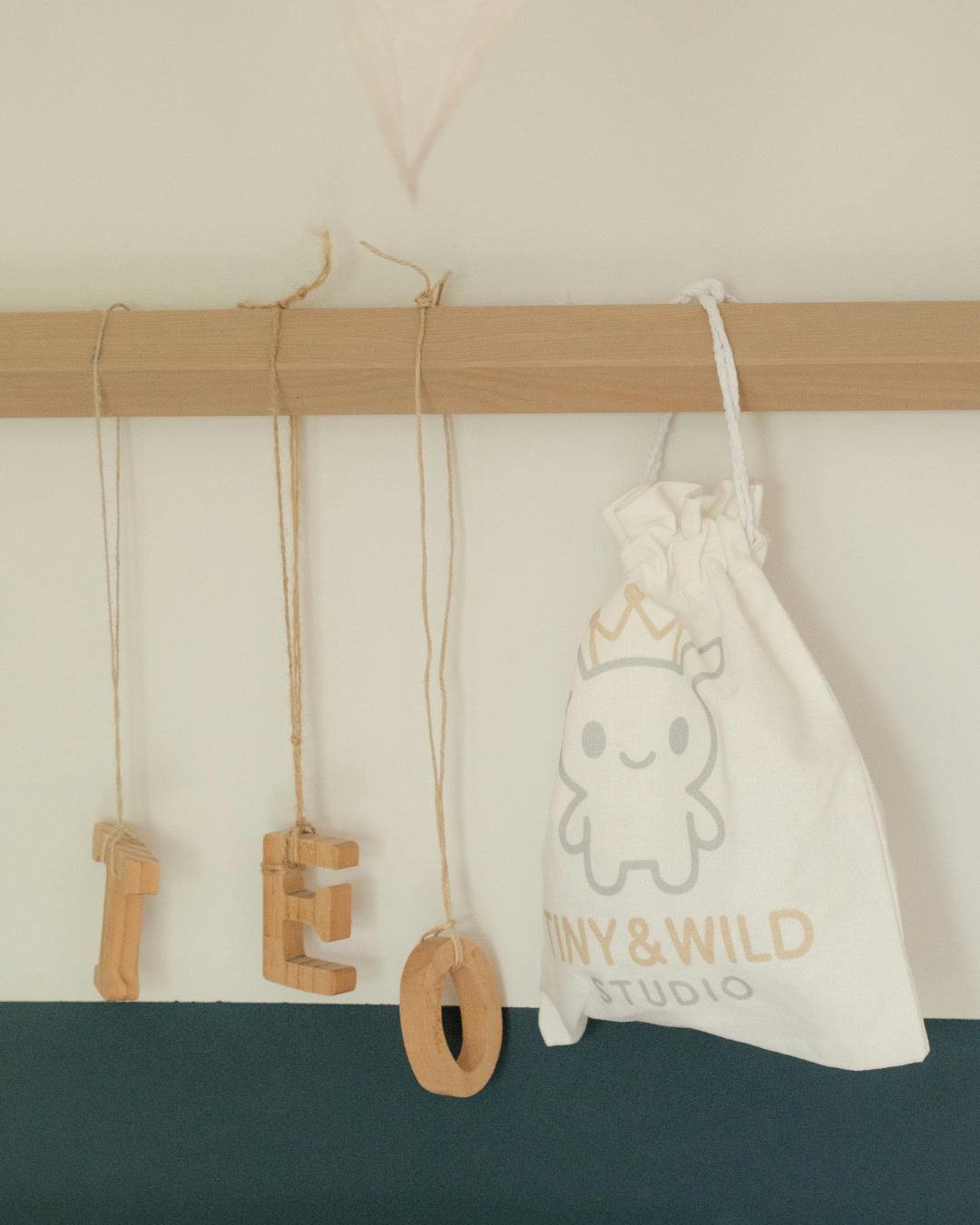 Tiny & Wild fabric gift bag hanging beside wooden letter ornaments
