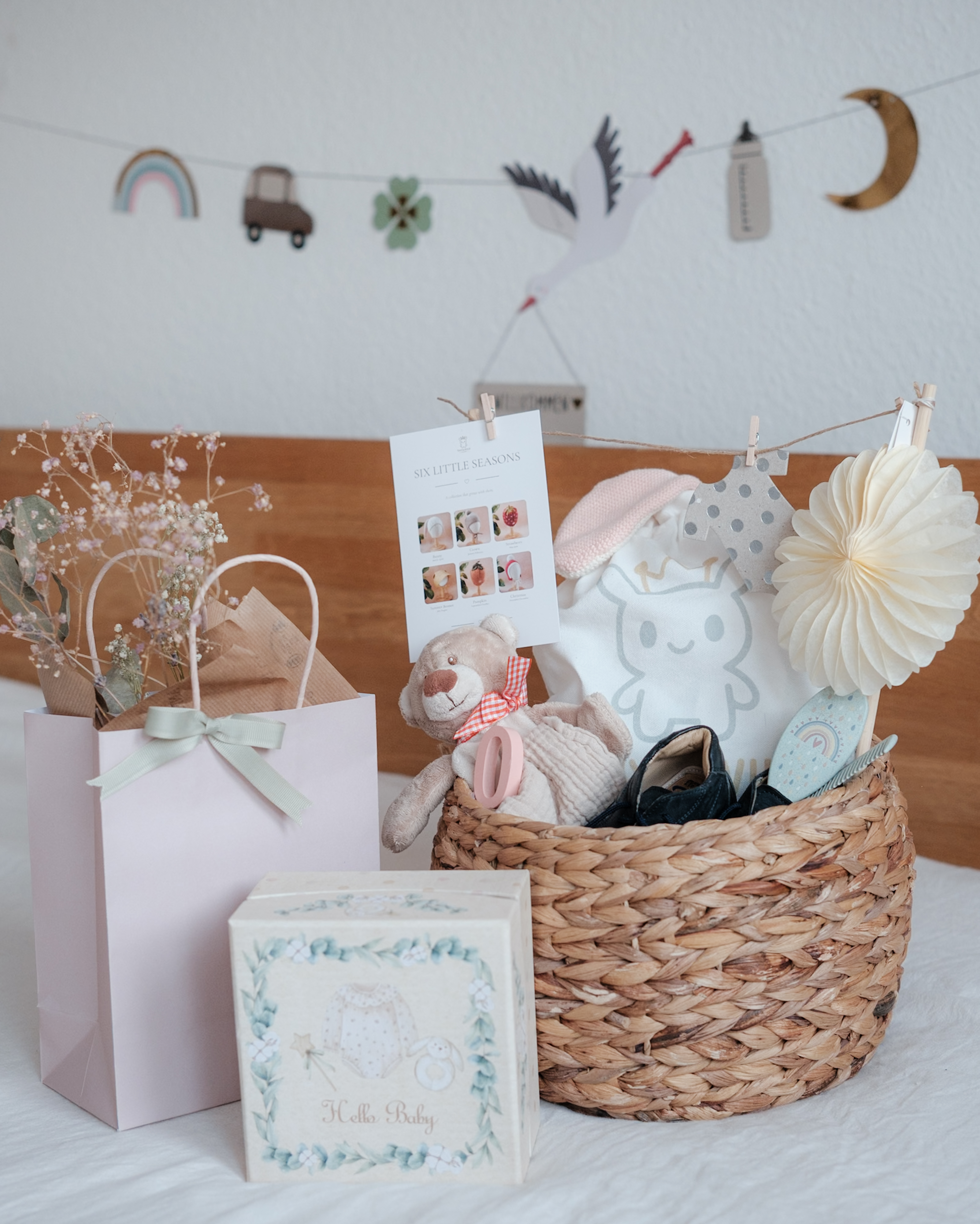 Baby gift basket with a teddy bear, Tiny & Wild fabric bag and Six Little Seasons card beside wrapped gifts