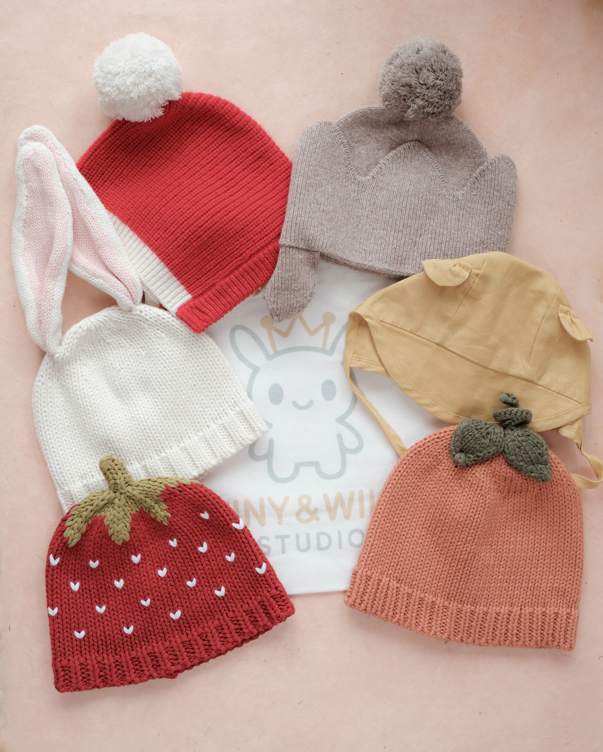 Six seasonal Tiny & Wild pieces arranged around the fabric gift bag on a soft blush background